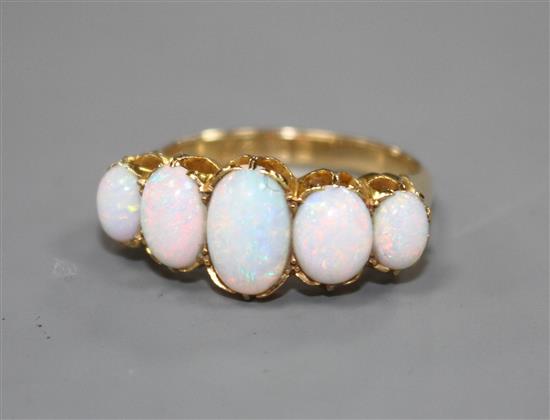 An Edwardian 18ct gold and graduated five stone white opal half hoop ring, size Q, gross 5.5 grams.